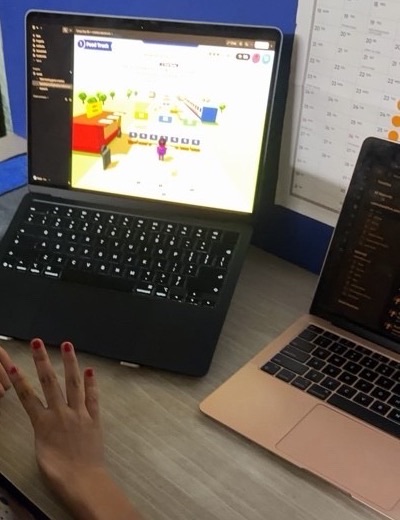 A child's hand next to a laptop showing an OMO game prototype during an at-home playtest